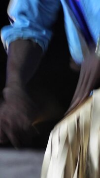 Vertical video of Black man in traditional clothes standing playing decorated sabar drum