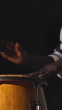 Vertical video of Black man standing playing conga drums in front of microphone