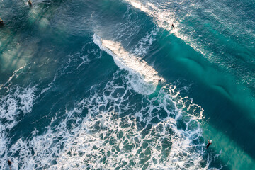 Fototapeta na wymiar Spectacular aerial view of a surfer taking on waves in a blue ocean