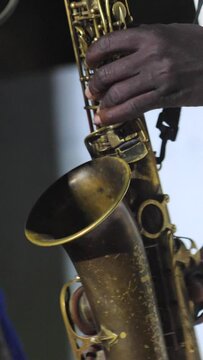 Vertical video of Black man playing the keys of a saxophone