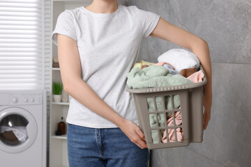 Woman with basket full of laundry in bathroom, closeup