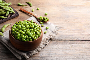Delicious edamame beans on wooden table, space for text