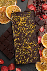 Different chocolate bars with freeze dried fruits on slate table, flat lay
