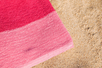 Fototapeta na wymiar Soft pink beach towel on sand, closeup. Space for text