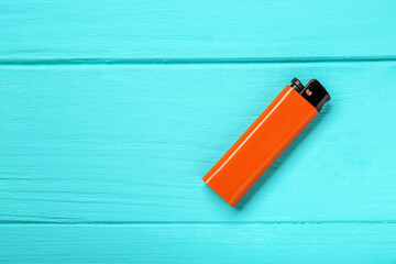 Stylish small pocket lighter on turquoise wooden background, top view. Space for text