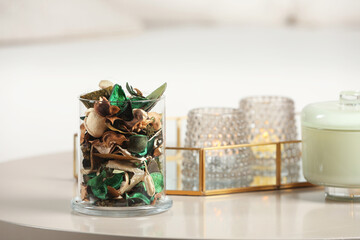 Aromatic potpourri of dried flowers in glass jar on white table indoors