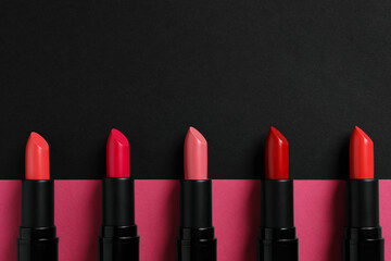 Beautiful lipsticks on black and pink background, flat lay. Space for text - obrazy, fototapety, plakaty