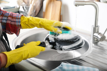 Woman washing dirty frying pan in sink indoors, closeup