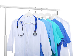 Doctor's gown with stethoscope and different medical uniforms on rack against white background