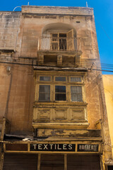 Fototapeta na wymiar Very old building with an ancient textiles shop in Gzira old town, Malta