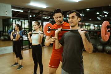 male instructor corrects body position when lifting barbells during joint training at the fitness center