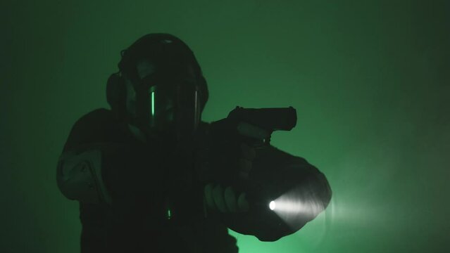 A man in a gas mask with a gun. Green background.