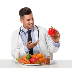 Male doctor with healthy food and drink sitting at table on white background