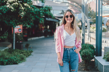 Empowered young woman smiling and standing on a sidewalk. Feminine determination