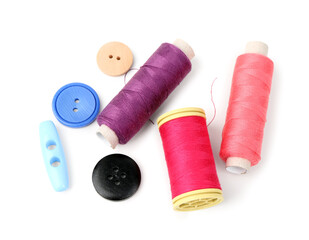 Colorful thread spools and buttons on white background