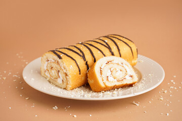 Plate with sweet sponge cake roll on color background