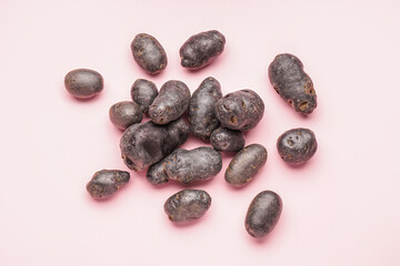 Raw purple potatoes on pink background