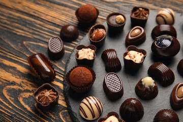 Slate board with chocolate candies on wooden background