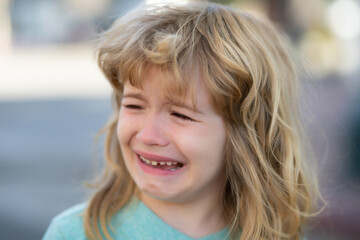 Portrait of crying kid with tears weeping emotion, hurt in pain. Tear drops on cheek.