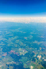 Fototapeta na wymiar Aerial view from airplane window above green ground. View from the airplane window with beautiful clouds at sunrise