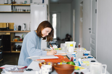Teengirl girl makes a card application of colored paper with the Snowman. The concept of creativity. Girl makes crafts, postcard, paper, multi-colored paper for creativity. Working from home. Hobby