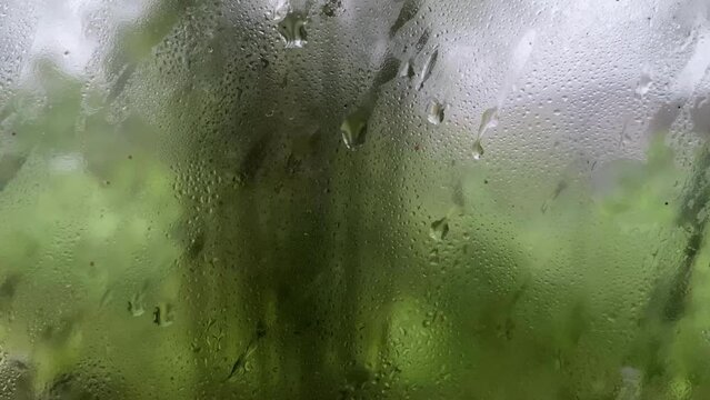 Rainwater flow on the window. Glass dripping with rainwater