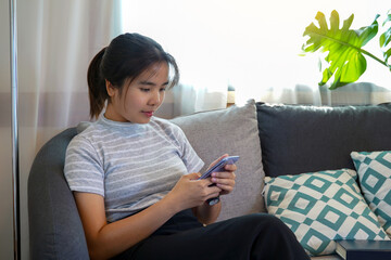 Obraz premium Asian woman Sitting on the sofa in the living room in the spare time, the concept of resting after work, relaxing, cozy corner, peaceful corner, nap. Soft and selective focus. 