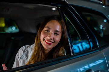 Asian businesswoman working late commuting from office in Taxi backseat with mobile phone in city at night after late work, Happy beautiful woman texting smartphone sitting car back seat in urban