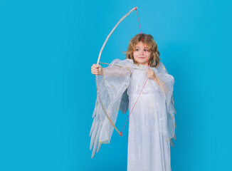 Cupids arrow hit right in heart, arrow of love. Angel with bow and arrow. Cute angel kid, studio portrait. Blonde curly little angel child with angels wings, isolated background.