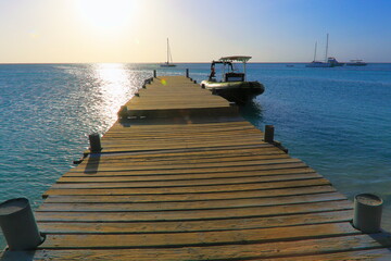 Obraz premium Pier on turquoise beach in Aruba at sunset, Caribbean Blue sea, Duth Antilles
