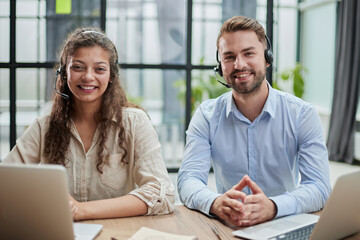 smilling man and charming woman are sitting at laptops in headphones