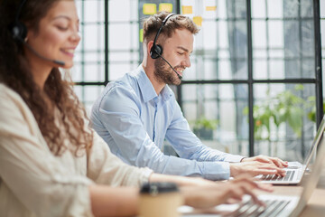 male call-center operator with headphones sitting at modern office