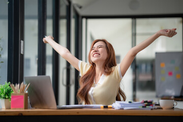 Young businesswoman stretching with hand raised while sitting on a chair in an office.