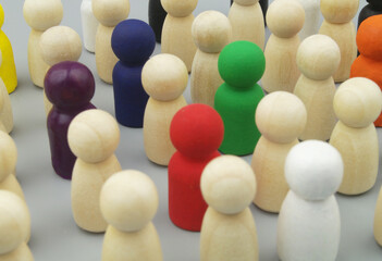Crowd of colored and not colored wooden people figures on gray background. People individuality and...