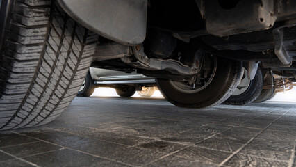 Abstract under view of undercarriage of the cars in the parking area. on black tile floor.