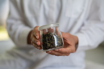 Woman in white clothes with mock up jar with green tea in hands