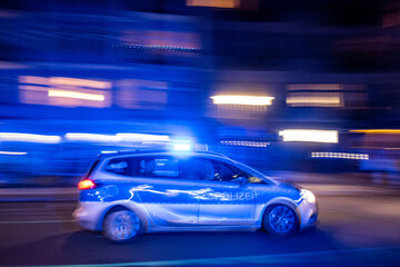 Fototapeta na wymiar Patrol car of the Berlin police drives with blue lights to a mission through Oderberger Straße in Berlin-Prenzlauer Berg on New Year's Eve.