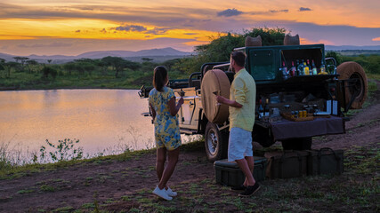 A couple of men and an Asian woman on safari in South Africa, a luxury safari car during a game...