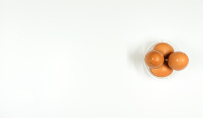 Top view of eggs in clear bowl on white background, isolated
