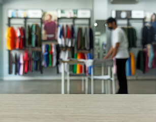 Empty brown wooden texture table and Defocused or Blurred background of clothing store with people activity bokeh image luxury and fashionable brand, can be used for montage or display your product