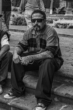 Cholo showing off his tattos and outfit