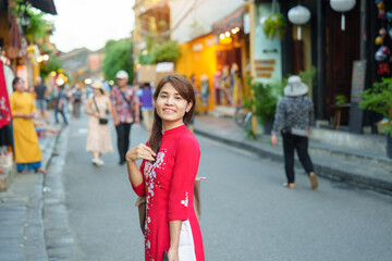 Fototapeta premium happy woman wearing Ao Dai Vietnamese dress, asian traveler sightseeing at Hoi An ancient town in central Vietnam. landmark and popular for tourist attractions. Vietnam and Southeast travel concept