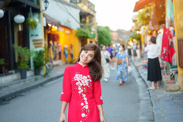 Fototapeta premium happy woman wearing Ao Dai Vietnamese dress, asian traveler sightseeing at Hoi An ancient town in central Vietnam. landmark and popular for tourist attractions. Vietnam and Southeast travel concept