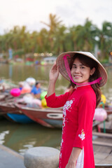 happy woman wearing Ao Dai Vietnamese dress, traveler visit Thu Bon River and Sightseeing Boat Ride at Hoi An ancient town. landmark for tourist attractions.Vietnam and Southeast travel concept