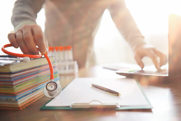 Male doctor search information in book and writtnig prescription, medical stethoscope on the desk at clinic. Medical knowledge and education concept.