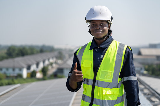 Portrait African American engineer man smiling working with solar panel on roof factory	
