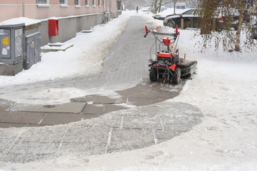 Snow plough removing snow on a pathway and street after snow blizzard during winter in Europe