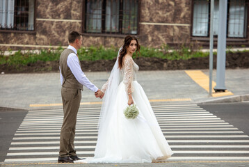 Fototapeta na wymiar The bride and groom in a wedding dress on a pedestrian crossing.