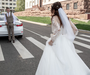 Obraz premium The bride and groom in a wedding dress on a pedestrian crossing.