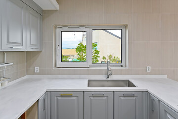A large window was placed in front of the sink to provide a sense of openness by removing...